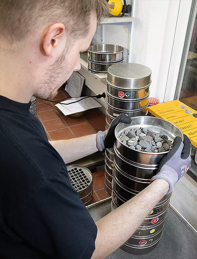 Mitarbeiter bei der Laborprüfung von Gesteinskörnungen mit Prüfsieben